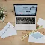 MacBook Pro beside white papers and plant