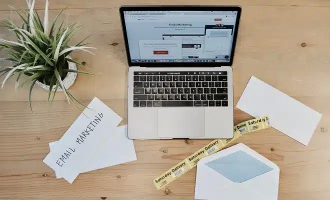 MacBook Pro beside white papers and plant